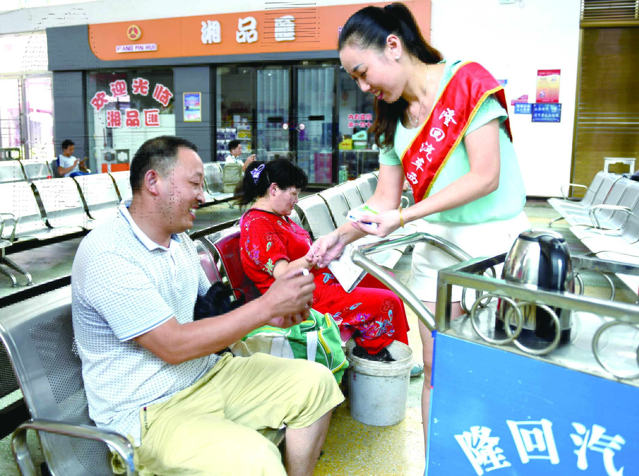 隆回分公司汽車西站工作人員正在為旅客免費(fèi)贈(zèng)送藿香正氣水。